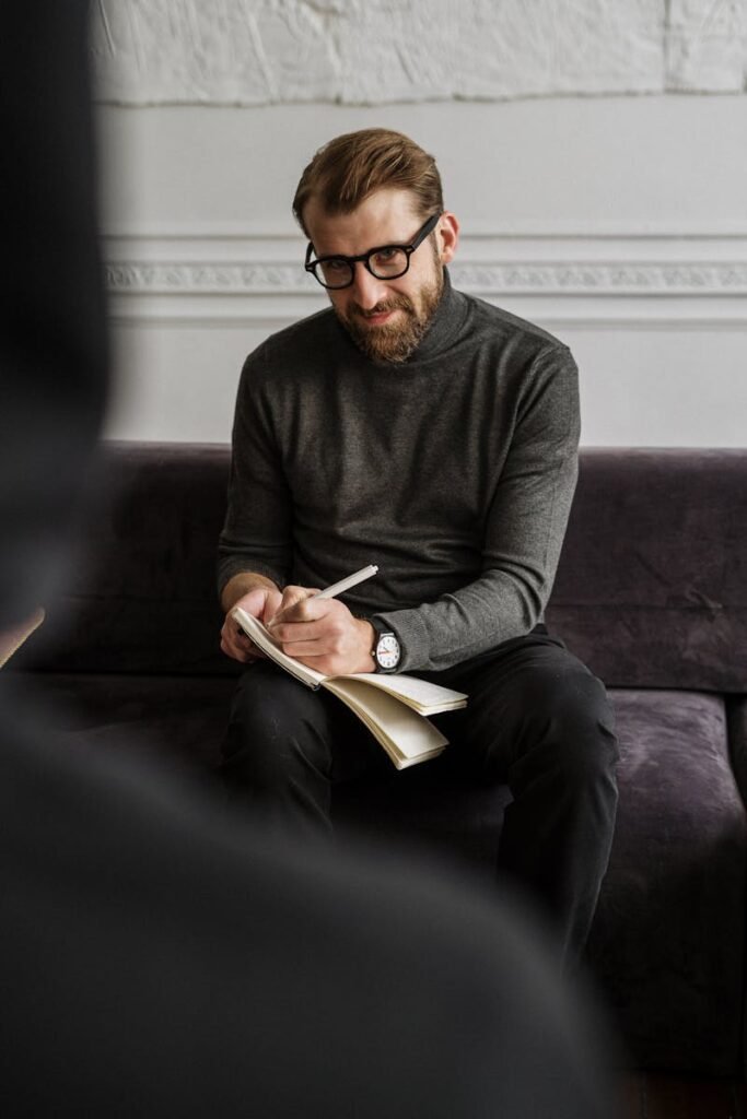 Equipo Mostoles Asesores Male professional in a cozy office setting taking notes during a session or meeting.